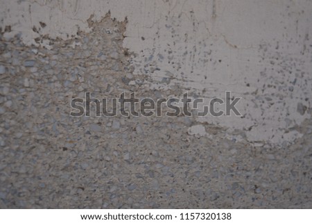 Reinforced concrete wall with cement mortar, small gray stones and white plaster
