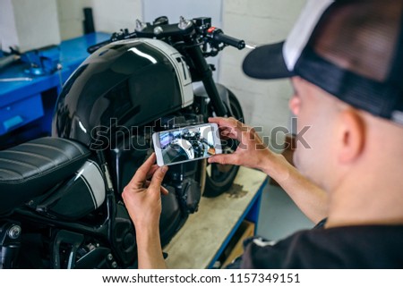 Mechanic taking picture of customized motorcycle just finished in the workshop