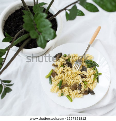 Homemade pasta with mushrooms and vegetables: beans and peas in a plate. Vegetarian food. Cozy home atmosphere. For a blog