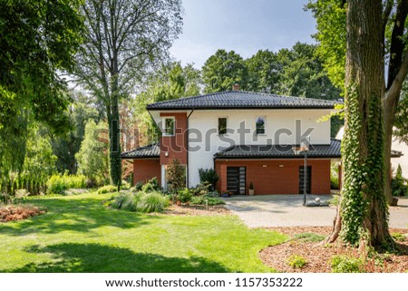 Modern house, garden with bushes and trees and basketball playground. Real photo