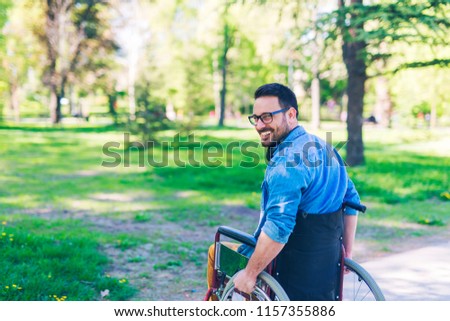 Young handicapped man in wheelchair enjoying at public park