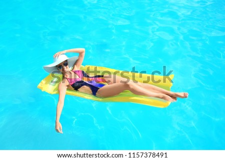 Beautiful young woman resting on inflatable mattress in pool