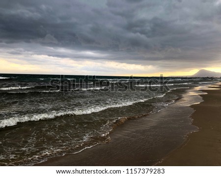 Landscape picture of the beach in Alicante on a stormy morning in summer with the cape of La Nao in the far background