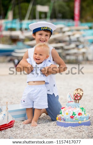 Sweet baby boy and his brothers, celebrating on the beach first birthday with sea theme cake and sea decoration