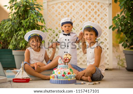 Sweet baby boy and his brothers, celebrating first birthday with sea theme cake and sea decoration