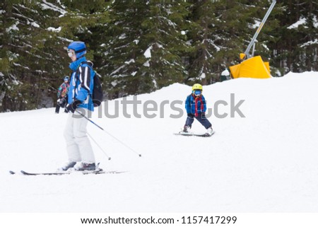Young preschool child, followed by his father, skiing on snow slope in ski resort in Austria, wintertime