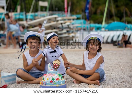 Sweet baby boy and his brothers, celebrating on the beach first birthday with sea theme cake and sea decoration