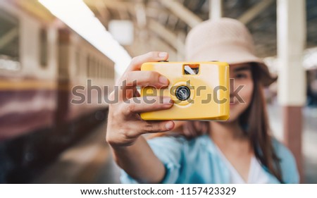woman travel by train, Girl with yellow plastic camera in hands, Travel lifestyle and seasonal vacation concept.