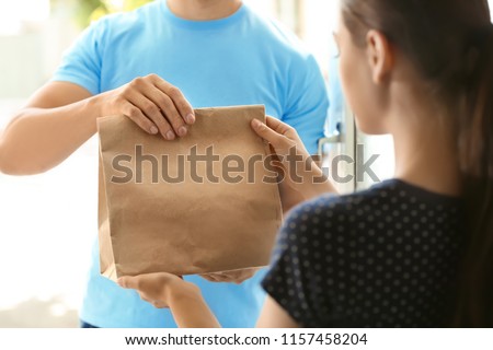 Young man delivering food to customer at doorway Royalty-Free Stock Photo #1157458204