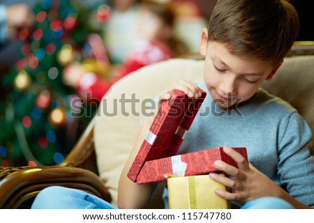 Portrait of adorable boy with giftboxes looking into one of them