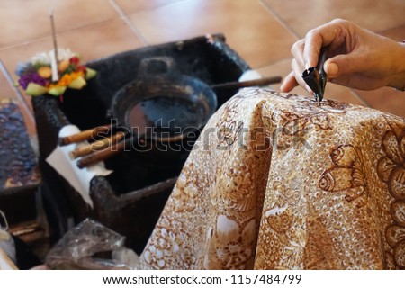 Balinese woman drawing batik pattern on white fabric Royalty-Free Stock Photo #1157484799