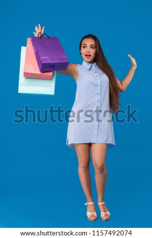 Photo of beautiful young woman with colorful shopping bags on the wonderful blue background
