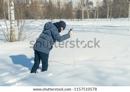 Boy teenager on skis in a park of winter snow drifts