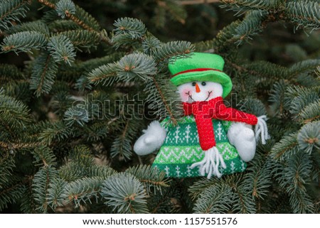 knitted snowman in a green cap and a red scarf on a Christmas tree