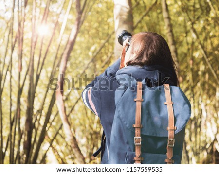 photographer and adventure in nature concept from beauty long hair asian woman in warm suit and backpack survey and take picture in tropical forest