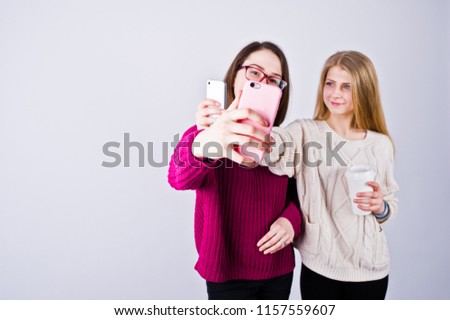 Two girls in purple dresses taking selfie in the studio.