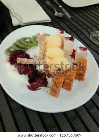 A delicious Spanish dessert with ice cream, kiwi and raspberry on a slate plate