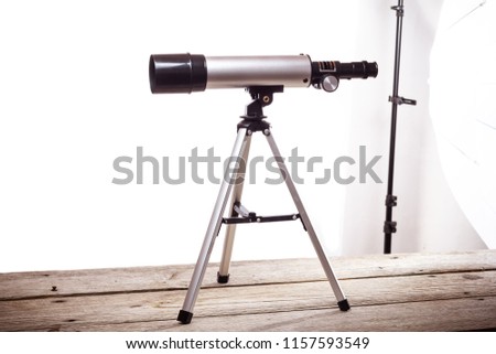 telescope on a white background laid on a rough wooden board