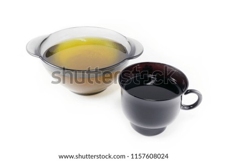 
Honey in a transparent plate and a black cup with tea on a white background
