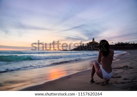 Pretty young woman on a beach at sunset with a camera in her hand