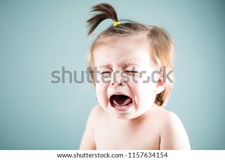 Miserable baby girl crying and looking very upset in a studio Royalty-Free Stock Photo #1157634154