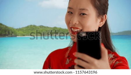 Close up of happy millennial woman taking selfie on a Caribbean beach