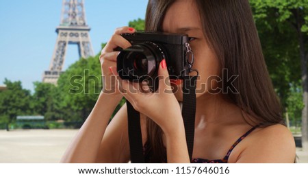 Close up of Asian millennial photographer taking photos by the Eiffel Tower
