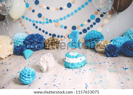First birthday cake. Smash cake. One year. Blue, brown, gold, beige, turquoise colors. Photo zone with paper garlands, balloons, paper honeycombs, confetti and cream cake.