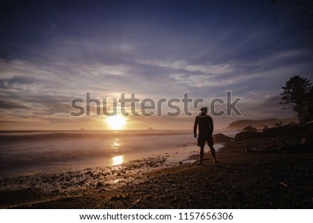 Silhouette of a lone man watching a beautiful sunset on the beach. 