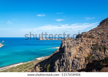 traveler with a backpack stands on a rock and takes pictures on the phone, Crete, Greece


