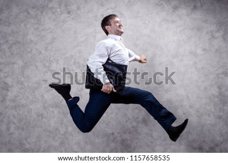 running businessman with briefcase on gray background