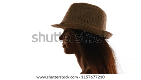 Silhouette of young woman in fedora on white background