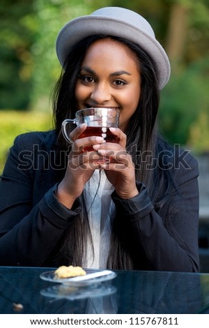 Beautiful Black Girl Smiling and Drinking Tea at an Outdoors Cafe
