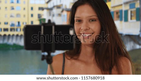 Gorgeous young traveler girl using selfie stick near Ponte Vecchio Bridge