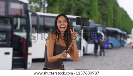 Cute brunette traveler girl on holiday in Europe using selfie stick