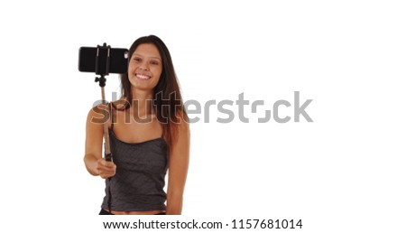 Pretty tourist woman with selfie stick posing for pictures on white background