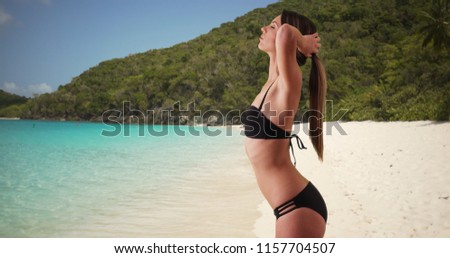 Side view of relaxed woman standing in swimsuit enjoying sun at the beach
