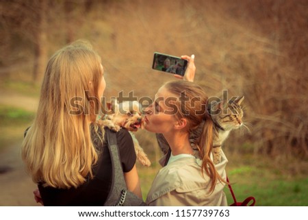 Selfy. A girl with a cat on her shoulder takes a girl and a dog
