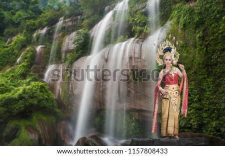 Beautiful woman wearing traditional thai dress with thai style in beautiful water fall in neture.