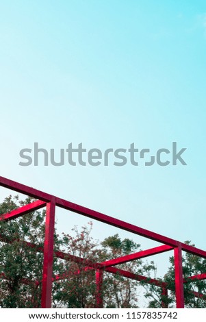 Abstract minimal red metal fixture architecture in tree park, Art geomatric shape construction in  outdoor design with blue sky