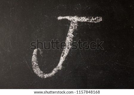 The letter "J" is drawn with chalk on a blackboard. Back to school. Education.