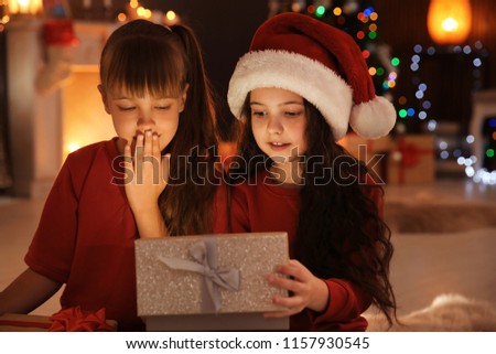 Cute little children with Christmas gift box at home