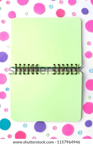 Open Notepad green pages on colored confetti background. Top view flat lay