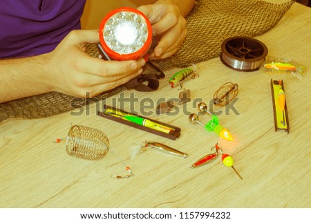 Fishing tackle - fishing spinning, hooks and lures on light wooden background. Close-up of a fisherman's hands with Accessories for fishing