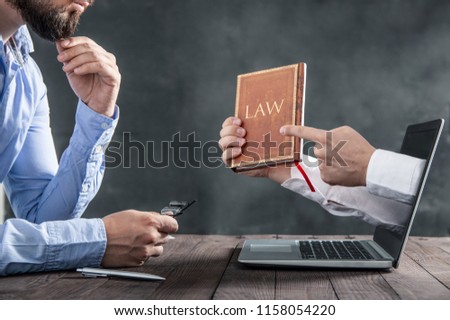 Man is looking at the hands coming out of the laptop that holds a book about the law. Metaphor of  law in the internet