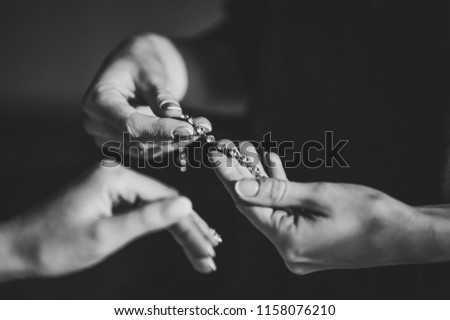 Bridesmaid helps to put a bracelet on his arm for the bride. bride putting on jewelry, focus on bracelet. Bridal preparation for the wedding ceremony. Black and white photo. Royalty-Free Stock Photo #1158076210