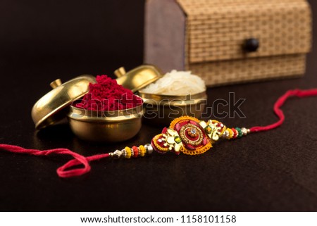 Raksha Bandhan background with an elegant Rakhi, Rice Grains and Kumkum. A traditional Indian wrist band which is a symbol of love between Brothers and Sisters.