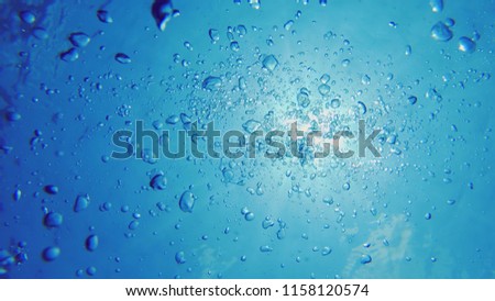 Underwater Shot Of Oxygene Bubbles Floating In The Sunlit Blue Sea Ascending Towards The Bright Surface.
