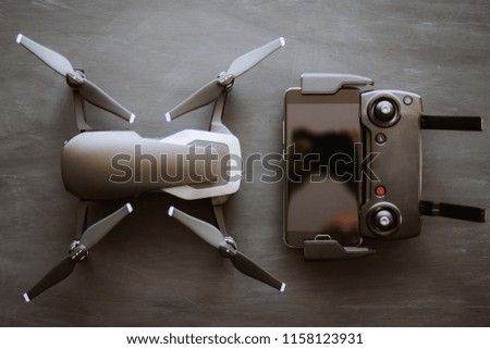 The concept of using drones in life and industry. Top view Remote and smartphone macro Details. Copy space. Innovation photography concept. Mate color. A new black drone on a black table.
