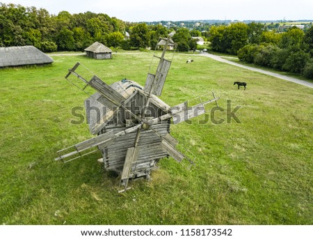 Aerial drone photo of old wooden windmills in green field shot from above